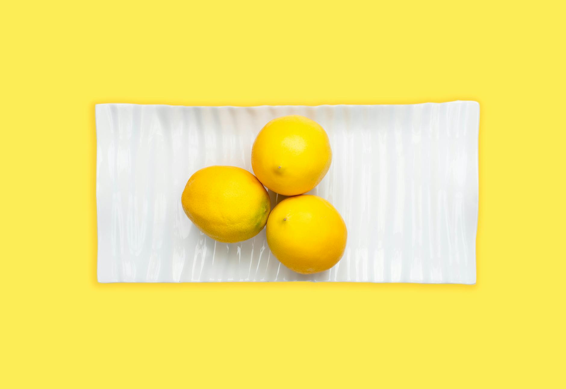 Hand holding a fresh lemon on a soft pink background, symbolizing gentle, fresh beginnings
