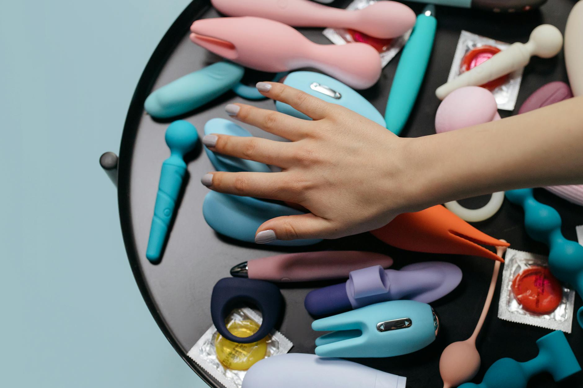 Hand holding a vibrator against a minimalistic purple backdrop