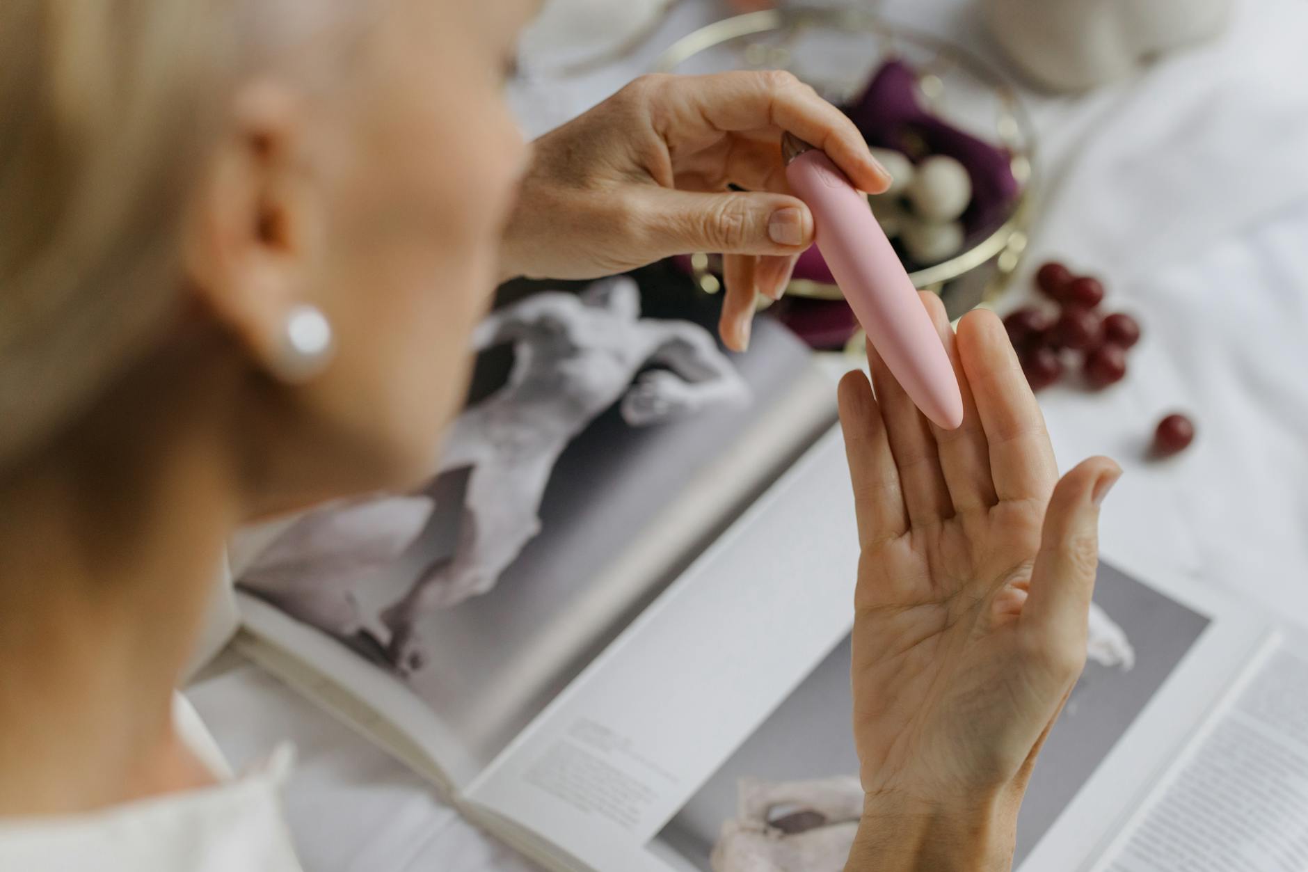 Hand reaching over a variety of colorful sex toys arranged on a table, showing options for partnered pleasure