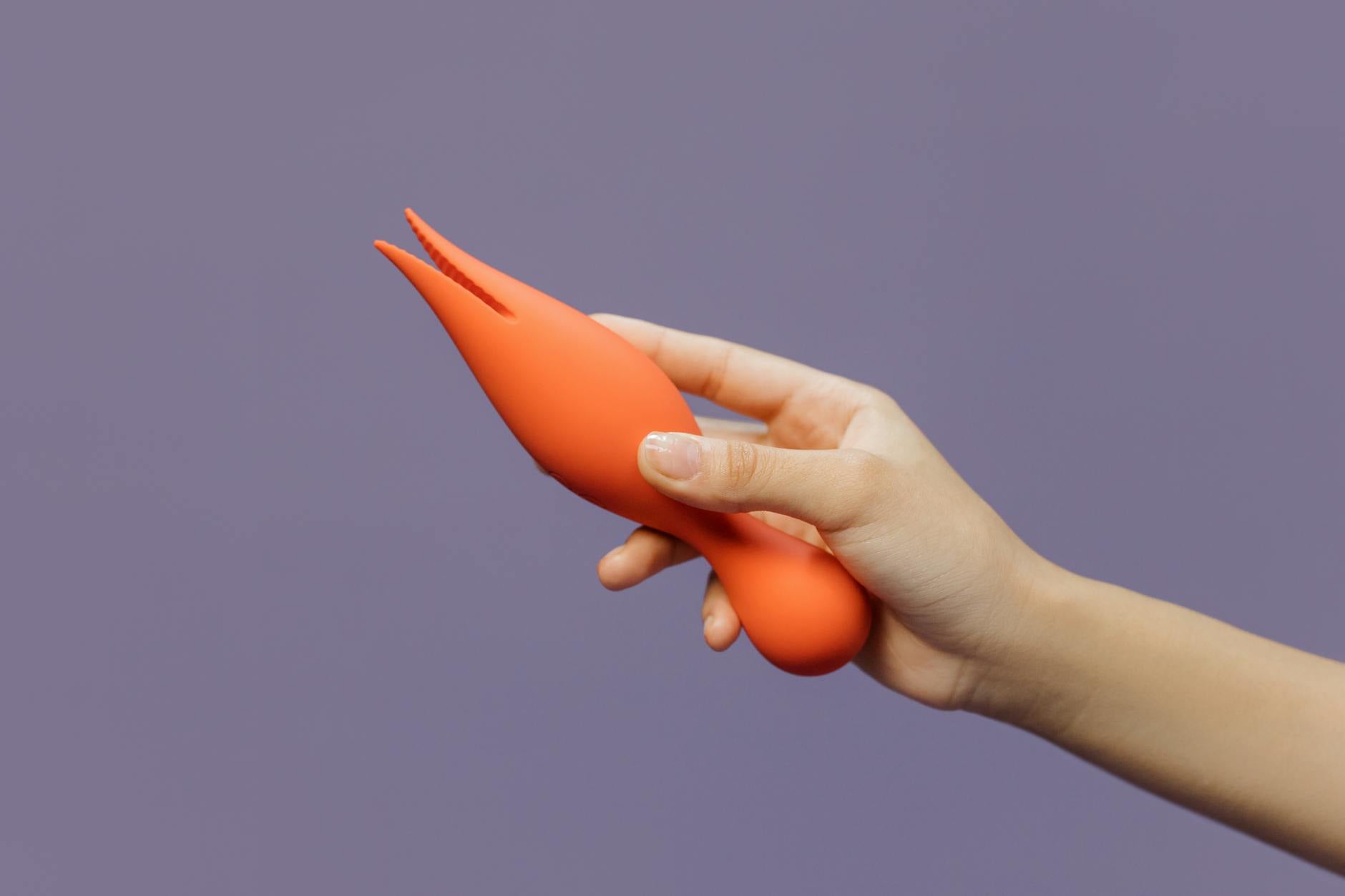 A hand holding a lemon vibrator against a minimalist purple backdrop, showcasing modern sensuality and pleasure.