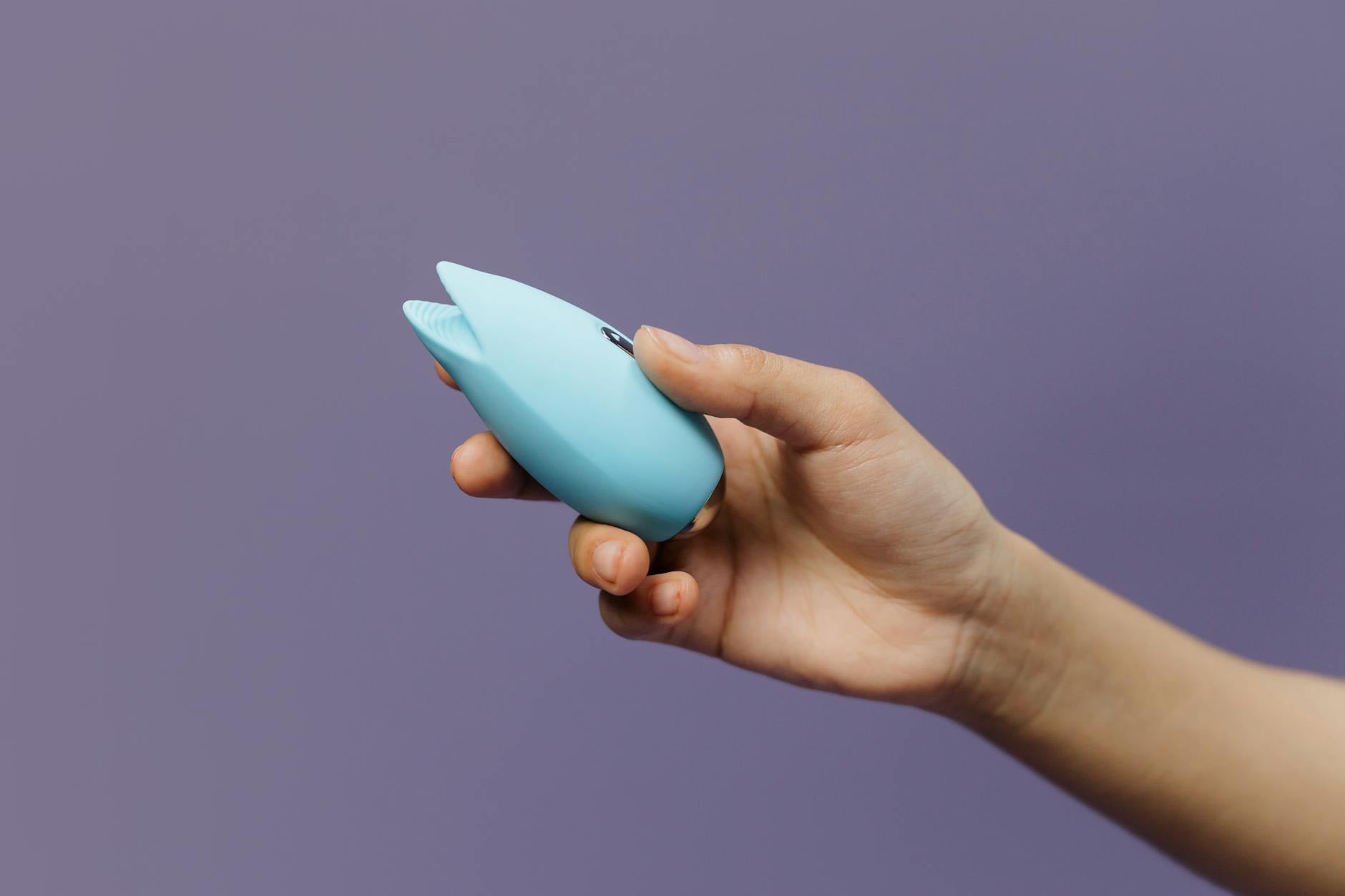 A blue silicone clitoral vibrator in hand, representing tools for reclaiming pleasure at any age.