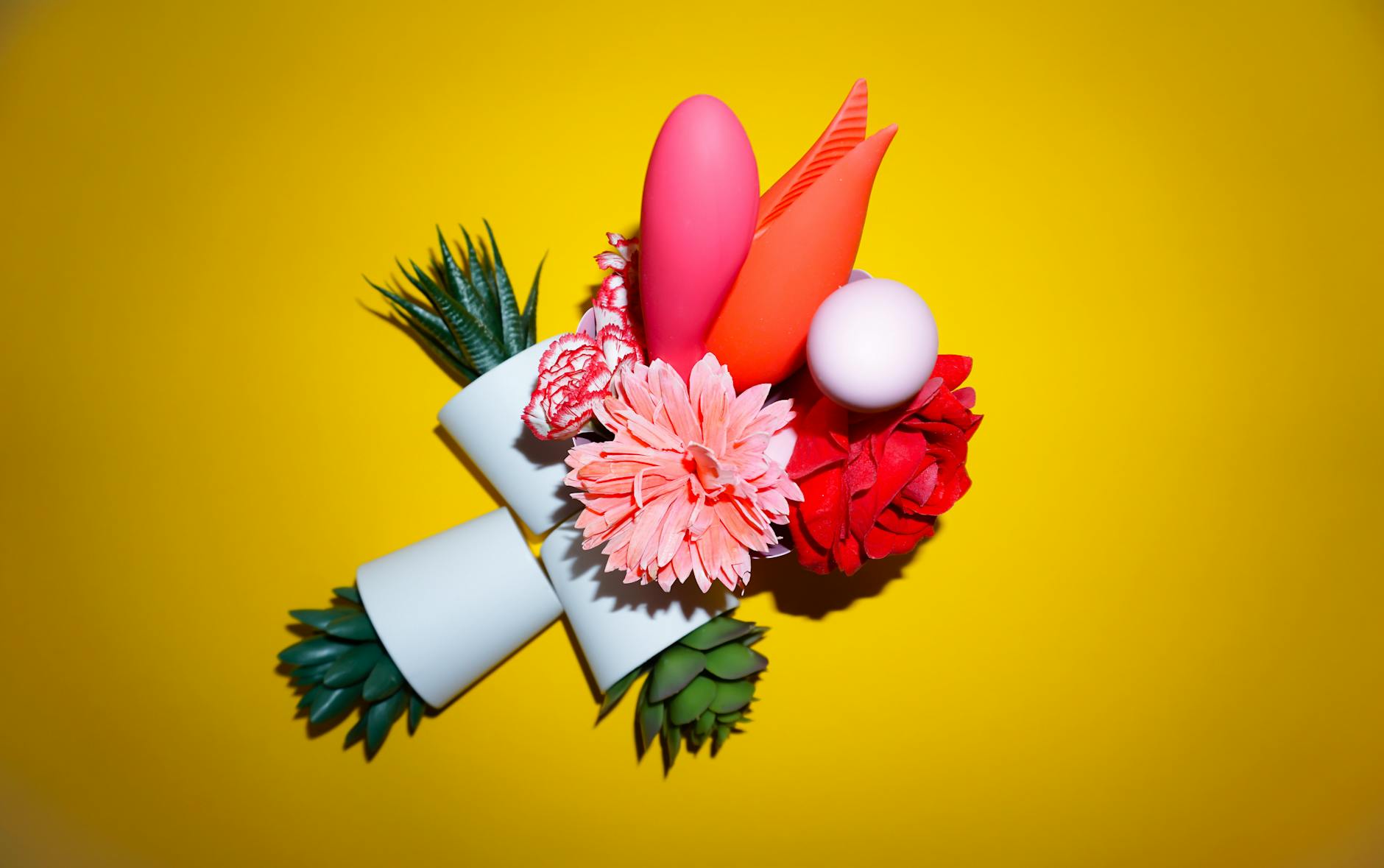 Colorful arrangement of vibrators and wellness objects on a bright yellow background